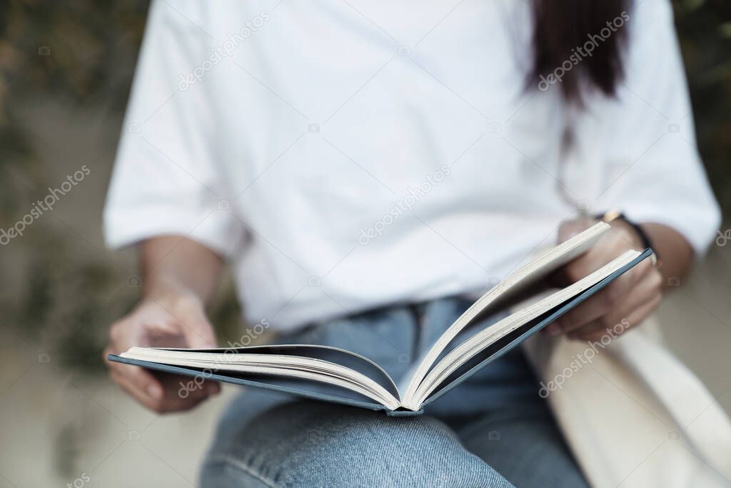 A book in a college girl's hands, she concentrate reading this book.