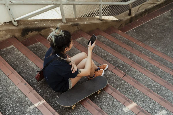 Ασιατική Κοπέλα Skateboard Χρησιμοποιώντας Κινητό Τηλέφωνο Στη Σκάλα — Φωτογραφία Αρχείου