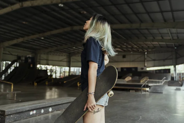 Asiatisches Mädchen Greift Mit Linker Hand Nach Skateboard — Stockfoto