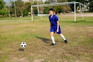 Küçük futbolcu oyun alanında tek başına futbol oynuyor..