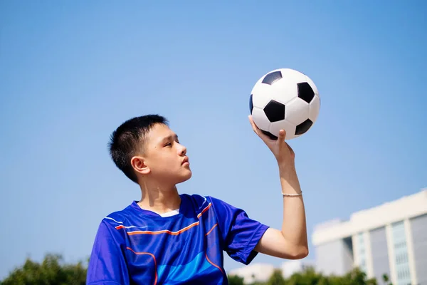 A litle football player catch the ball by one hand.