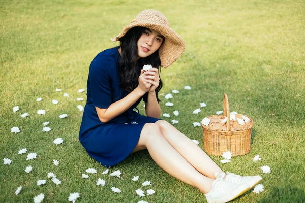 白い花を手にしたまま草原に座って祈っている美しいタイ人の少女 — ストック写真