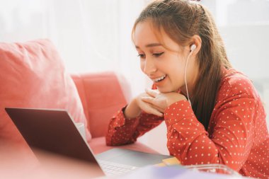 Ev konseptinden çalış. Kırmızı pijamalı güzel bir kadın kulaklık kullanıyor. Laptopta arkadaşlarıyla konuşmaktan zevk alıyor. Rahat ol. Karantina.