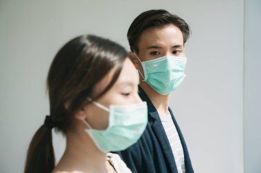 Doktor maskesi takan Asyalı bir çift Covid-19 'un dışarı çıkmasını engellemek için evde kalıyor. İnsanlar evde kalıyor. Karantina.