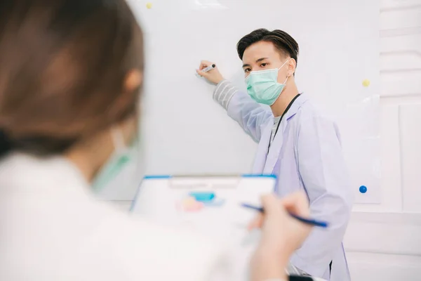 Handsom asian doctor preseting inside meeting room with team about how to help people during corona covid19 virus epidemic.