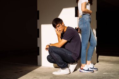 Taylandlı bir çift, sütunun başında duran erkek arkadaşının yanında oturan bir adam..