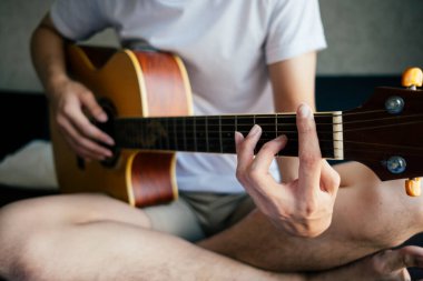 Oturan ve gitar çalan adam.