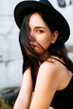 Siyah şapkalı güzel Taylandlı kadın vahşi gözlerle bakıyor..