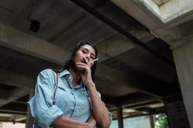 Havalı thai kızı kameraya bakarken sigara içiyor..