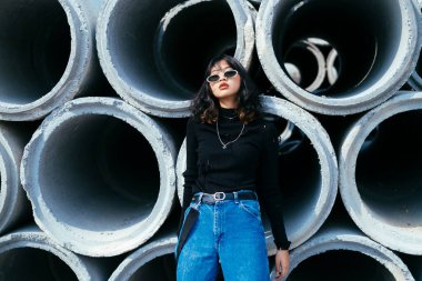 Beton tüplerin önünde duran genç kızın portresi..