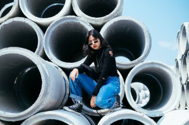 Beton tüplerde oturan genç bir kızın portresi..