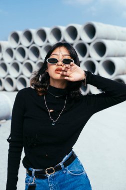 Arka planda çimento tüpleri olan Taylandlı kızın portresi..