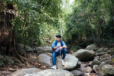 Yürüyüşten sonra bir kayanın üzerinde dinlenen bir adam..