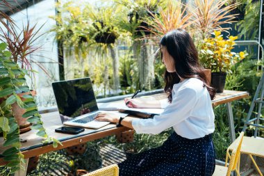 Kafede oturan bir kadın kağıda yazı yazıyor..