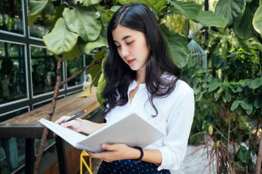 Not defterinden bilgi okuyan Asyalı kadın.
