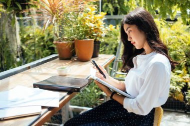 Cep telefonuna bakan ve bilgisayarını tutan tatlı bir kız..