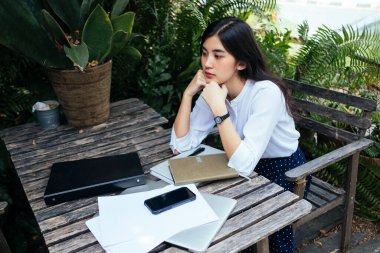 Kız bir bahçede iki eliyle çenesini kaldırır..