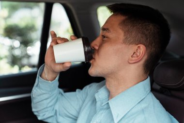 İş adamı, ofisine giderken arabada kahve içiyor..