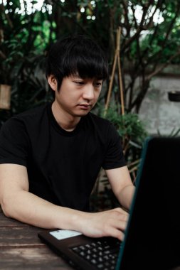 Kafenin bahçesinde çalışan siyah tişörtlü serbest çalışan bir adam..