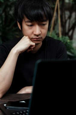 Siyah tişörtlü bir adam işinin sorunu ve çözümü hakkında düşünceli hissediyor..