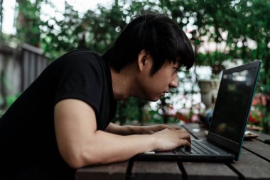 Siyah tişörtlü bir adam bilgisayardaki işine yakından bakıyor..