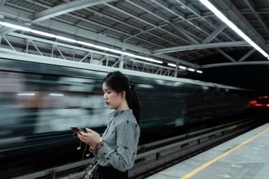 Platformda duran bir kadın polis memuru trenle değil, cep telefonuyla ilgileniyordu..