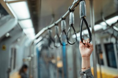 Tren boşken bir trenin gidonunu sallayan bilezikli bir kadının elini yakın plan çek..
