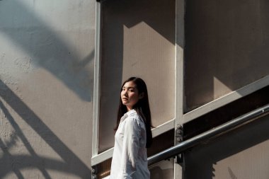 Yazın güçlü güneş ışığıyla parlayan inşaatın önünde duran bir kadın..