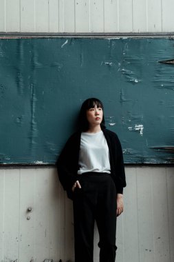 Beyaz duvardaki karatahta yıkık dökük ama kız görmezden geliyor..