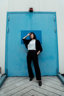 Siyah ve beyaz kadın binanın kapısında manken gibi duruyor..