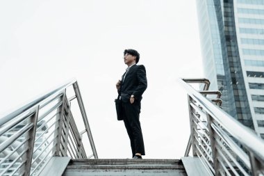 Genç işadamı şehrin merdivenlerinin ortasında duruyor ve bir şeye bakıyor..