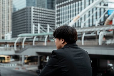 Şehrin gökyüzünde dikilirken dikkatsiz genç CEO 'su işini düşünüyor..