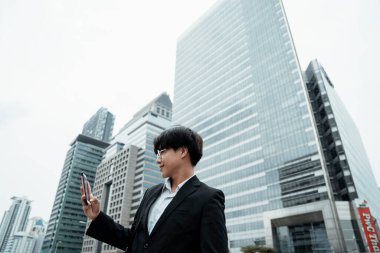 Genç işadamı ofisin dışındayken akıllı telefonunu video görüşmesi için kullanıyor..