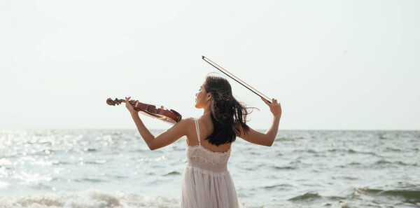 Girl playing violin on the sea.