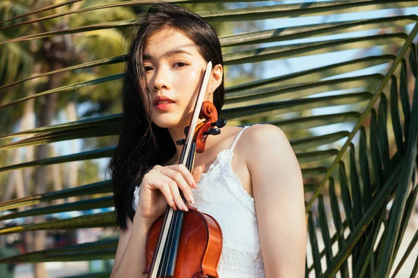 Portrait of woman and violin with coconut leaf on background.