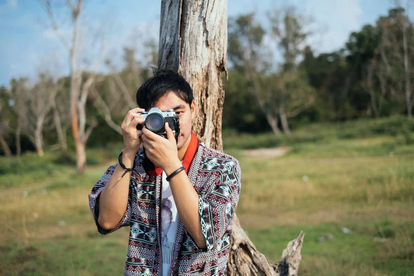 Kamerayı tutan ve kurumuş ağaca yaslanan adam..