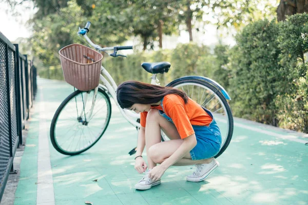 Menina Amarrando Seu Sapato Com Bicicleta Fundo — Fotografia de Stock