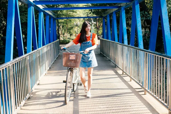 青い色の橋の上を自転車で歩くかわいい女の子 — ストック写真