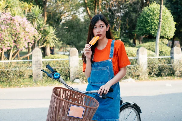かわいい女の子は自転車でアイスクリームを食べるのを楽しむ — ストック写真