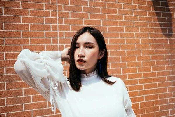 Hermosa Mujer Vestido Blanco Mirando Cámara Delante Pared Ladrillo — Foto de Stock