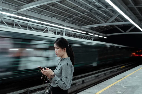 Platformda duran bir kadın polis memuru trenle değil, cep telefonuyla ilgileniyordu..