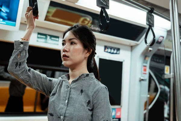 Trendeki bir subay kadın ayakta dururken gidonu sallıyor..