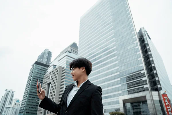 Genç işadamı ofisin dışındayken akıllı telefonunu video görüşmesi için kullanıyor..