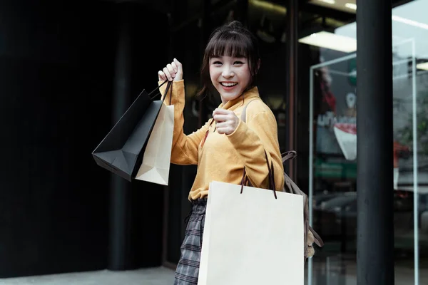 かわいいです女の子身に着けている黄色のセーター保持カップルの紙袋 — ストック写真