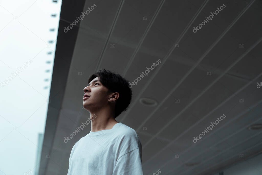 Teenager guy standing infront of the building and face up to the sky.