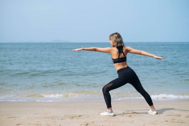 Spor kızı yazın plajda yoga yapıyor..