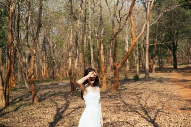 Sonbahar ormanlarında yüzünü güneş ışığından koruyan tatlı bir kız..