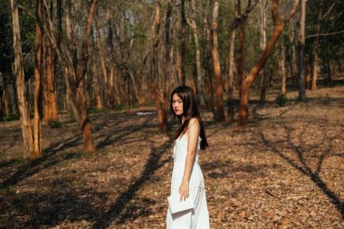 Sonbahar ormanında kameraya bakarak kitap tutmak çok hoş..