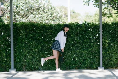 Tek bacaklı, arka planda çim duvarı olan tatlı bir kız..