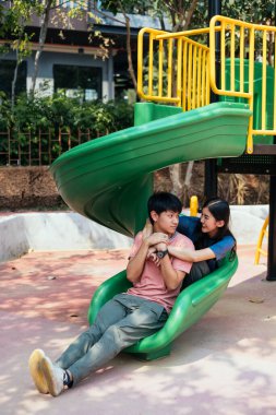 Asyalı çift yeşil oyun parkında sarılıyor..